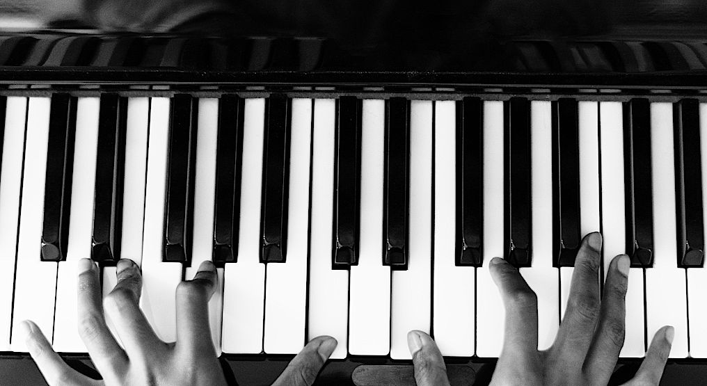 A black and white photo of hands playing a piano